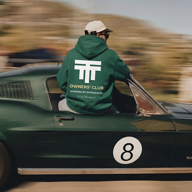 Person wearing a green hoodie with 'Twenty Two Tuning Owners Club' logo sitting on a vintage car.